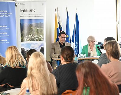 Udeleženci konference sedijo na stolih in spremljajo potek konference. V ospredju sedijo predstavniki Mestne občine Koper in Slovenskega društva Hospic.