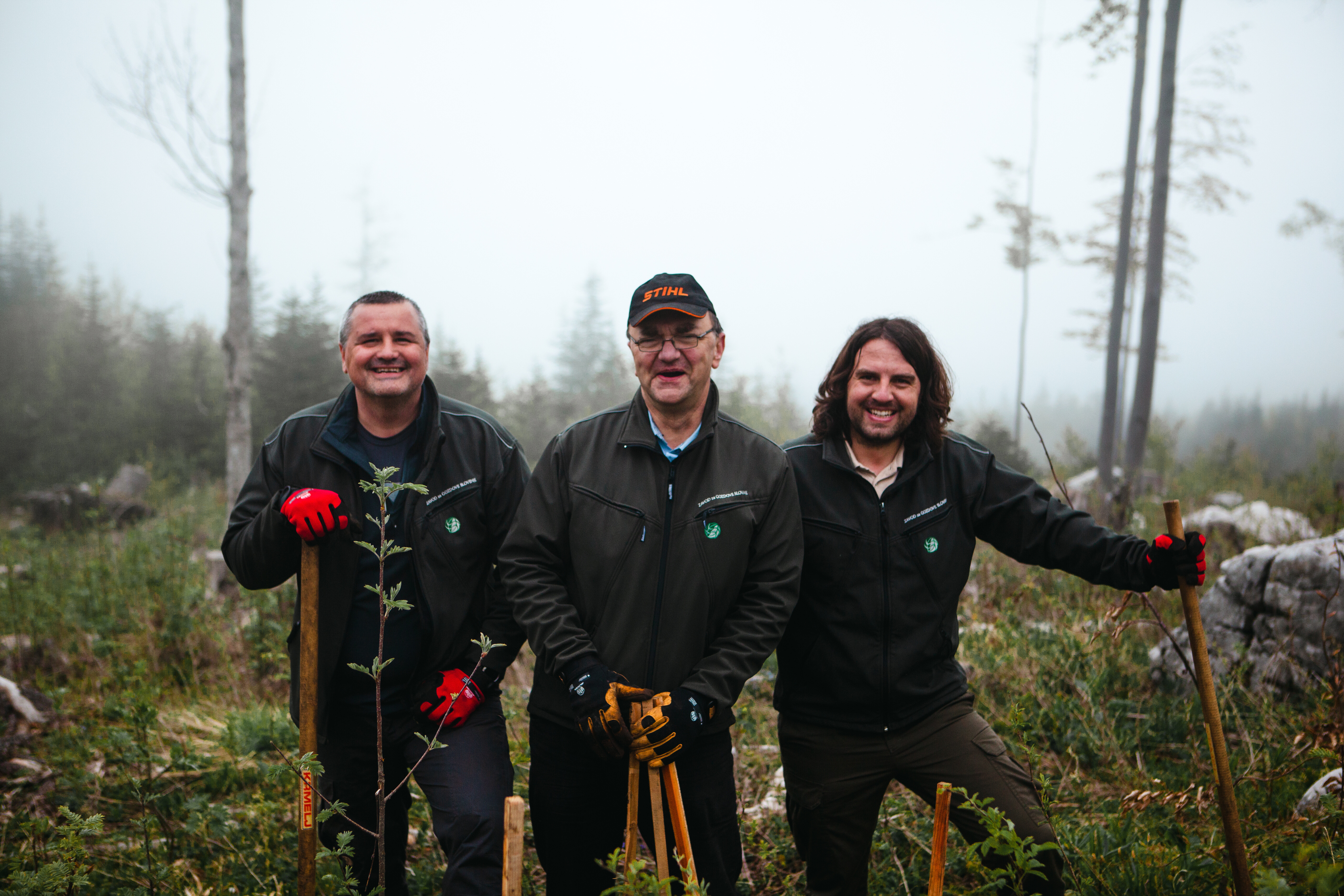 A group of three happy people in the middle of the forest