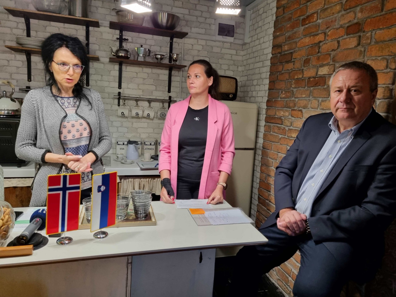 Three people at the kitchen counter in a shipping container.