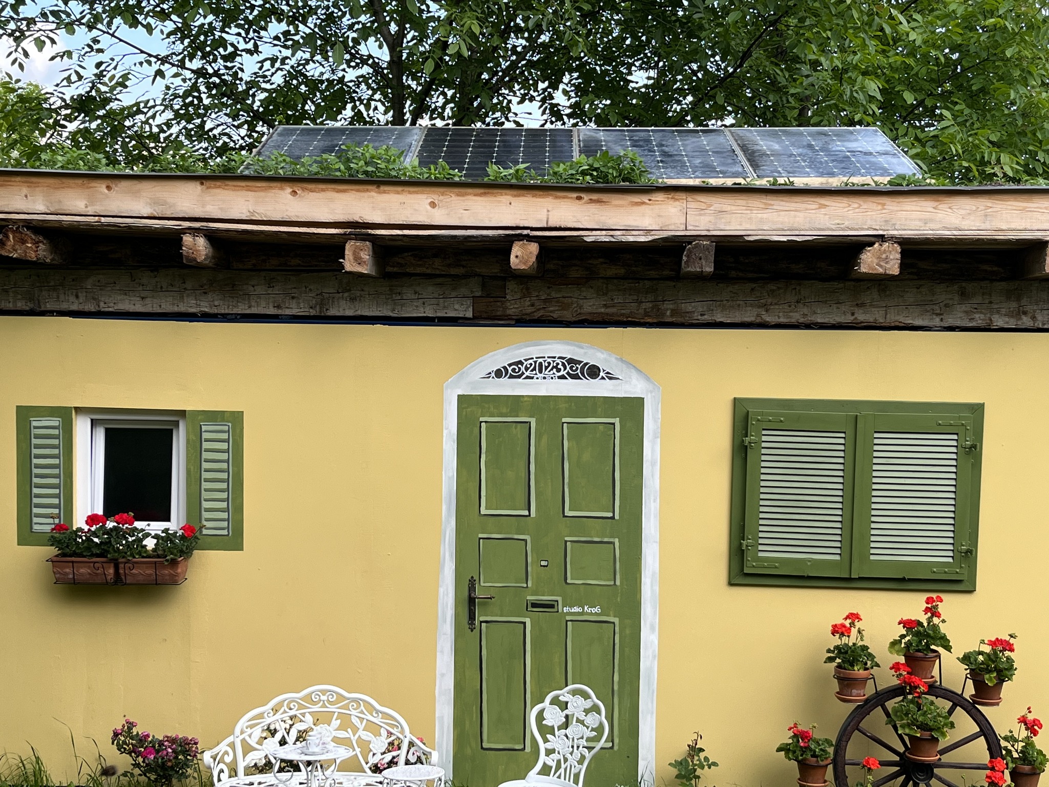 A shipping container painted like a house with windows and doors