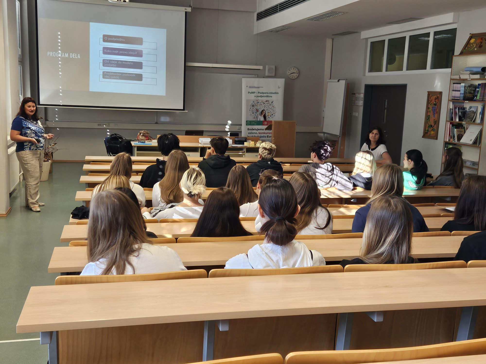 A group of students in a classroom sitting at tables and listening to a lecturer