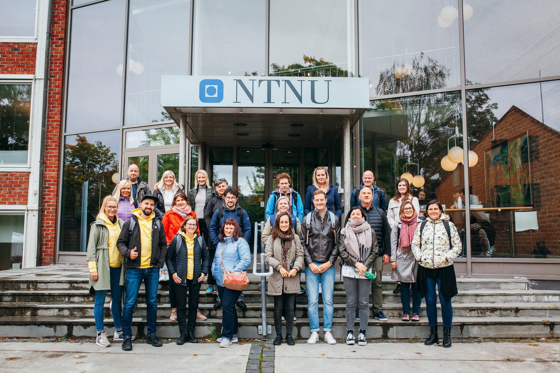 Group picture of study visit participants in front of the entrance to the NTNU building.