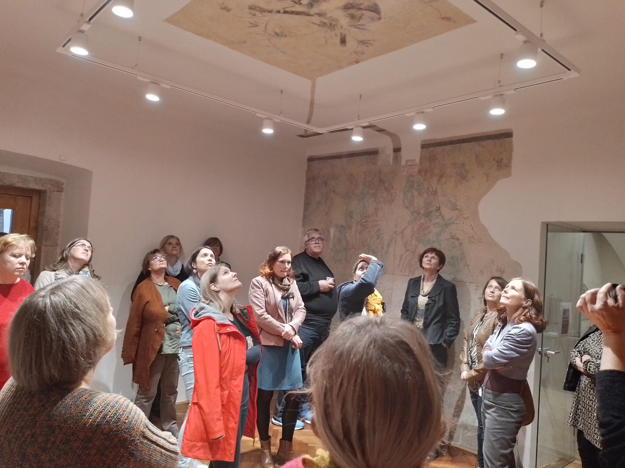 a group of people looking up at the ceiling, where part of the ceiling shows how it used to be worked