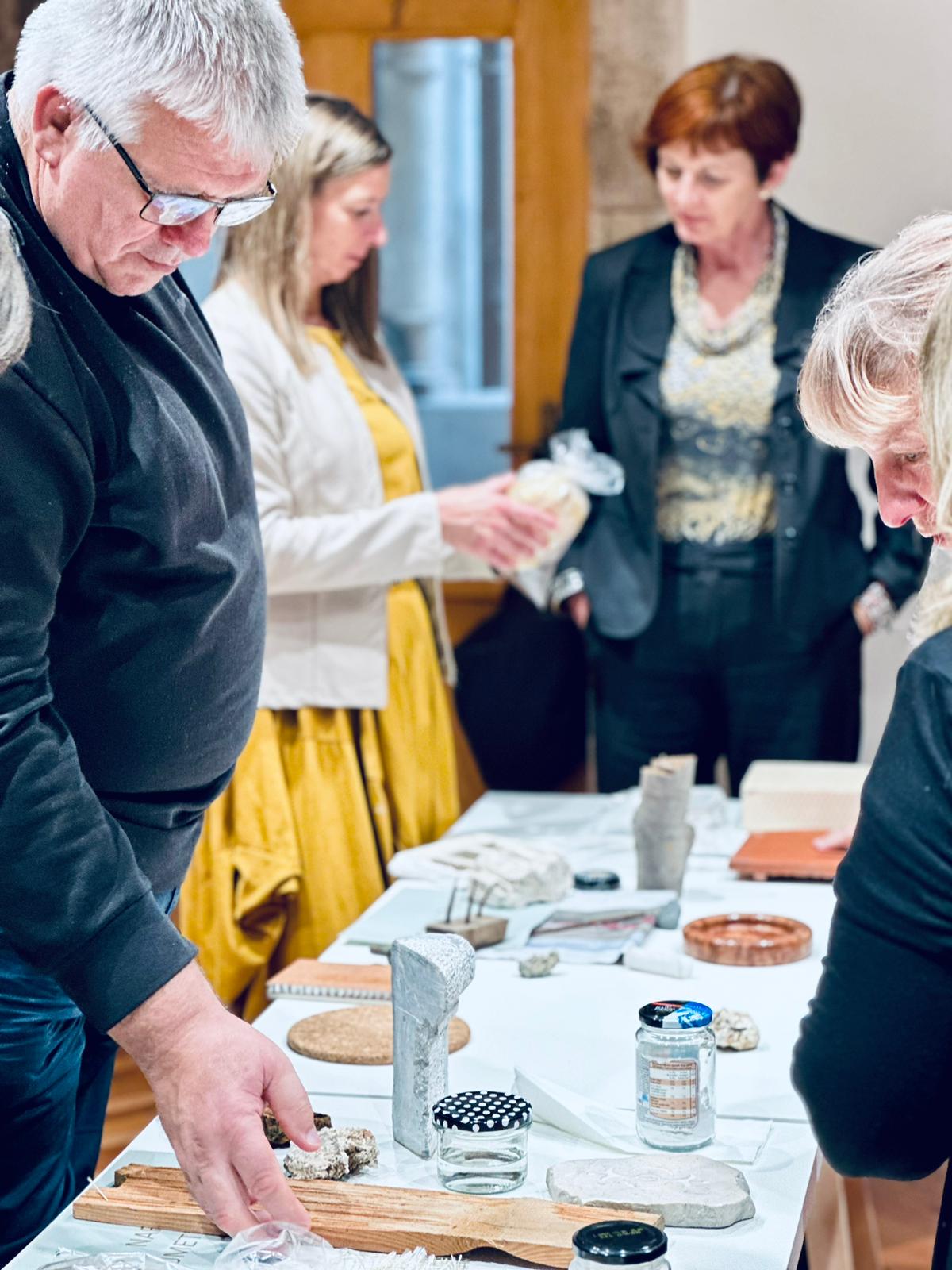 People gathered around a table looking at different wood and stone patterns
