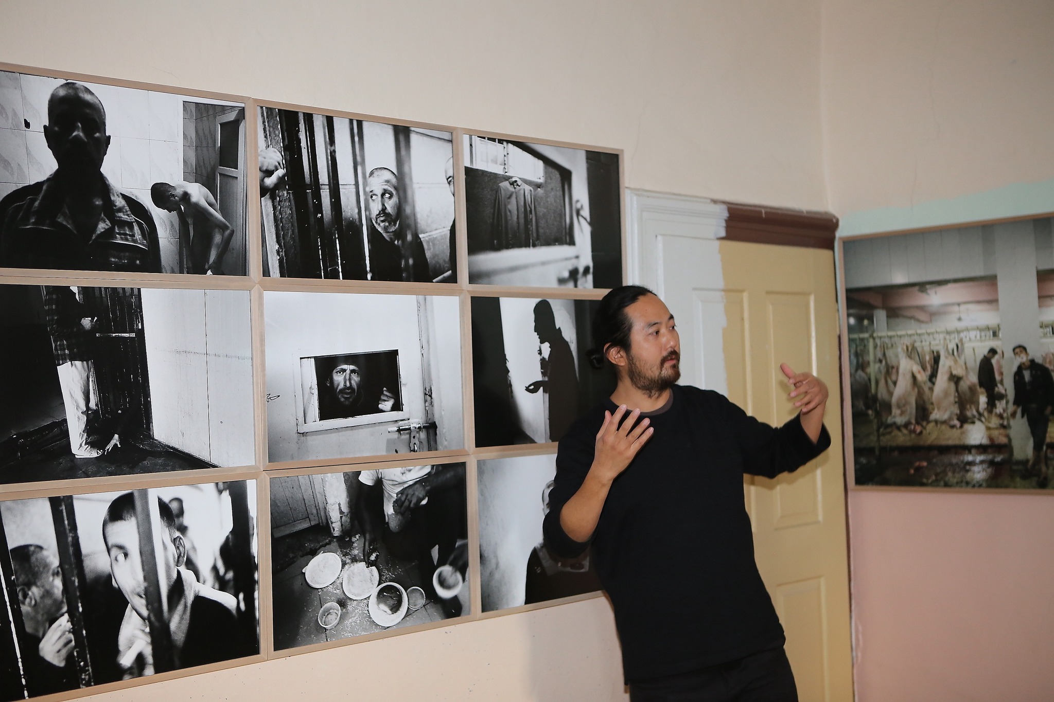 A gentleman explaining in front of a wall where black and white photographs are pasted
