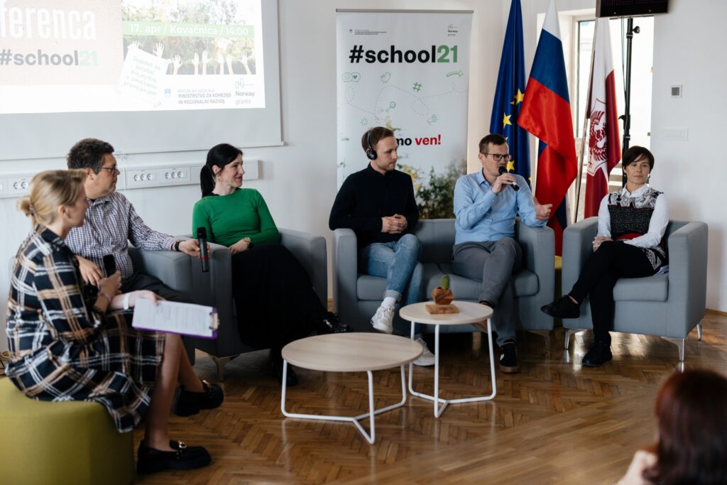 Participants of a round table sit on chairs and talk. 