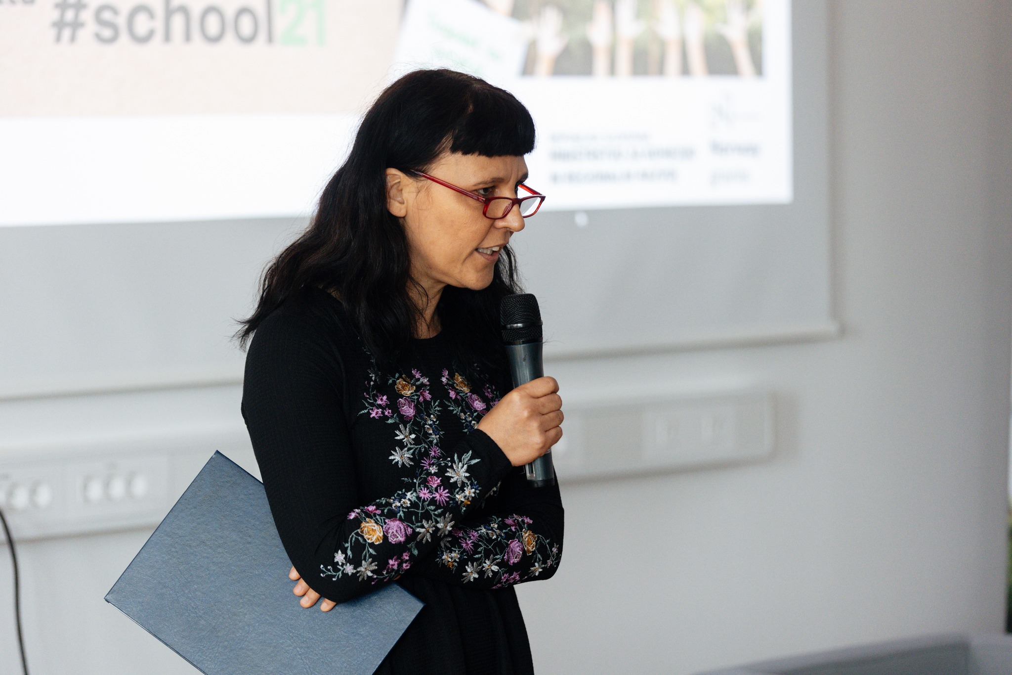 Jadranka Plut stands on stage with a microphone in her hand and gives her opening speech.