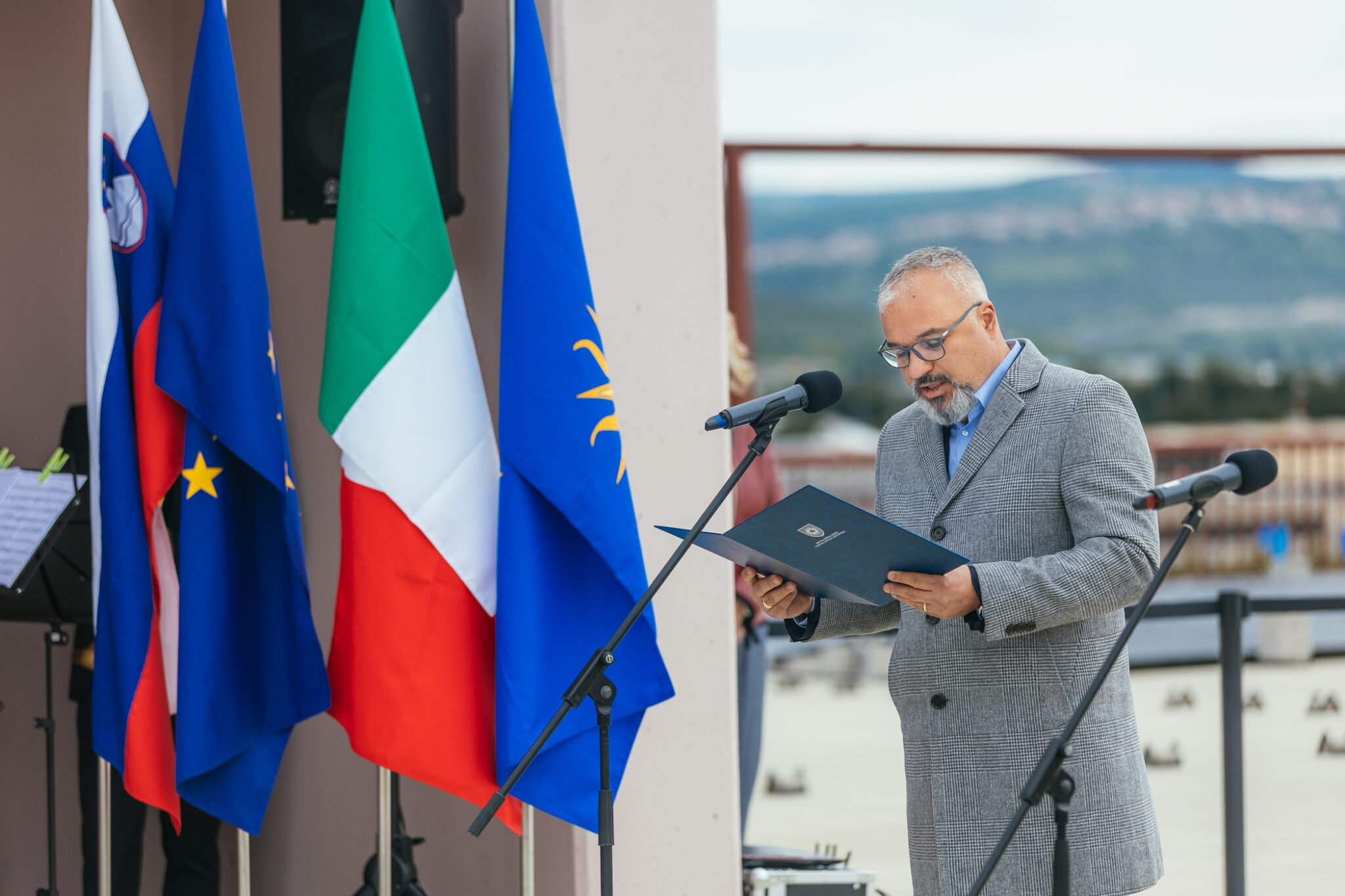 A man stands in front of a standing microphone and gives a speech.