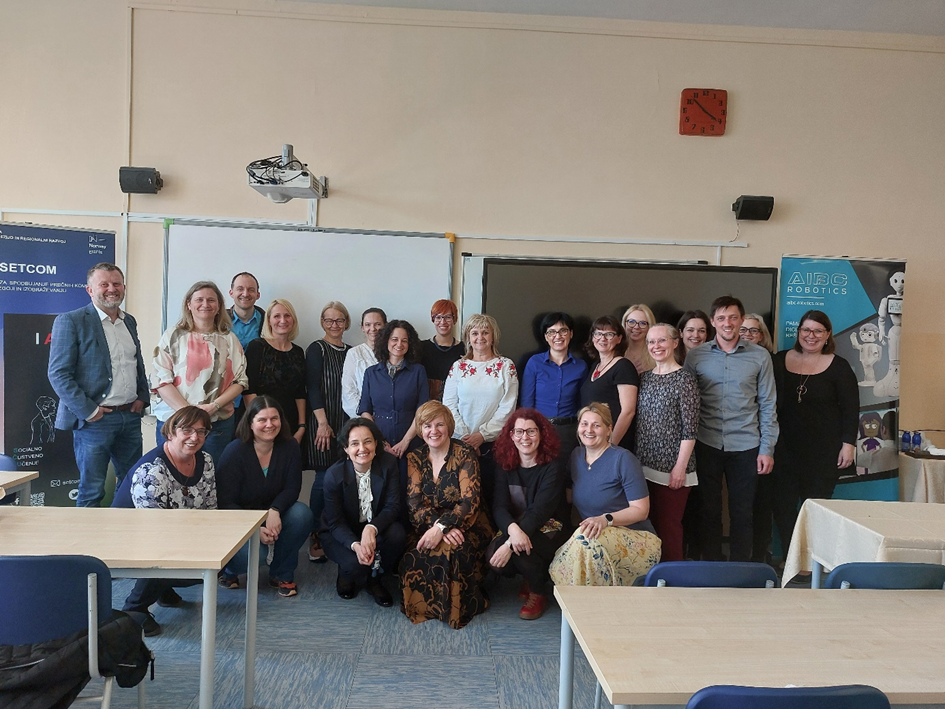 A group of people stand in front of a blackboard in a classroom and pose for a photo.