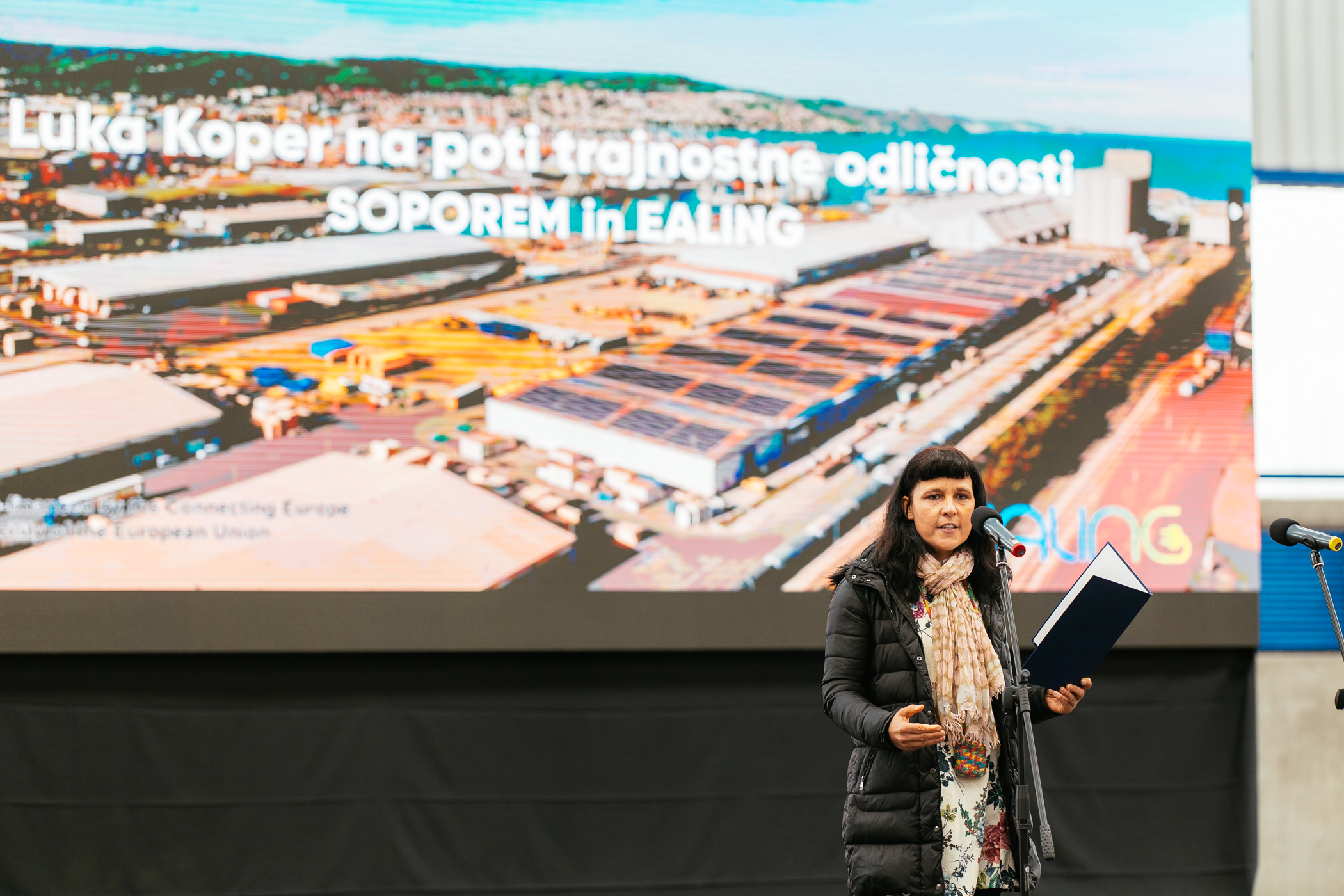 Jadranka Plut stands on stage in front of a standing microphone and delivers a speech.