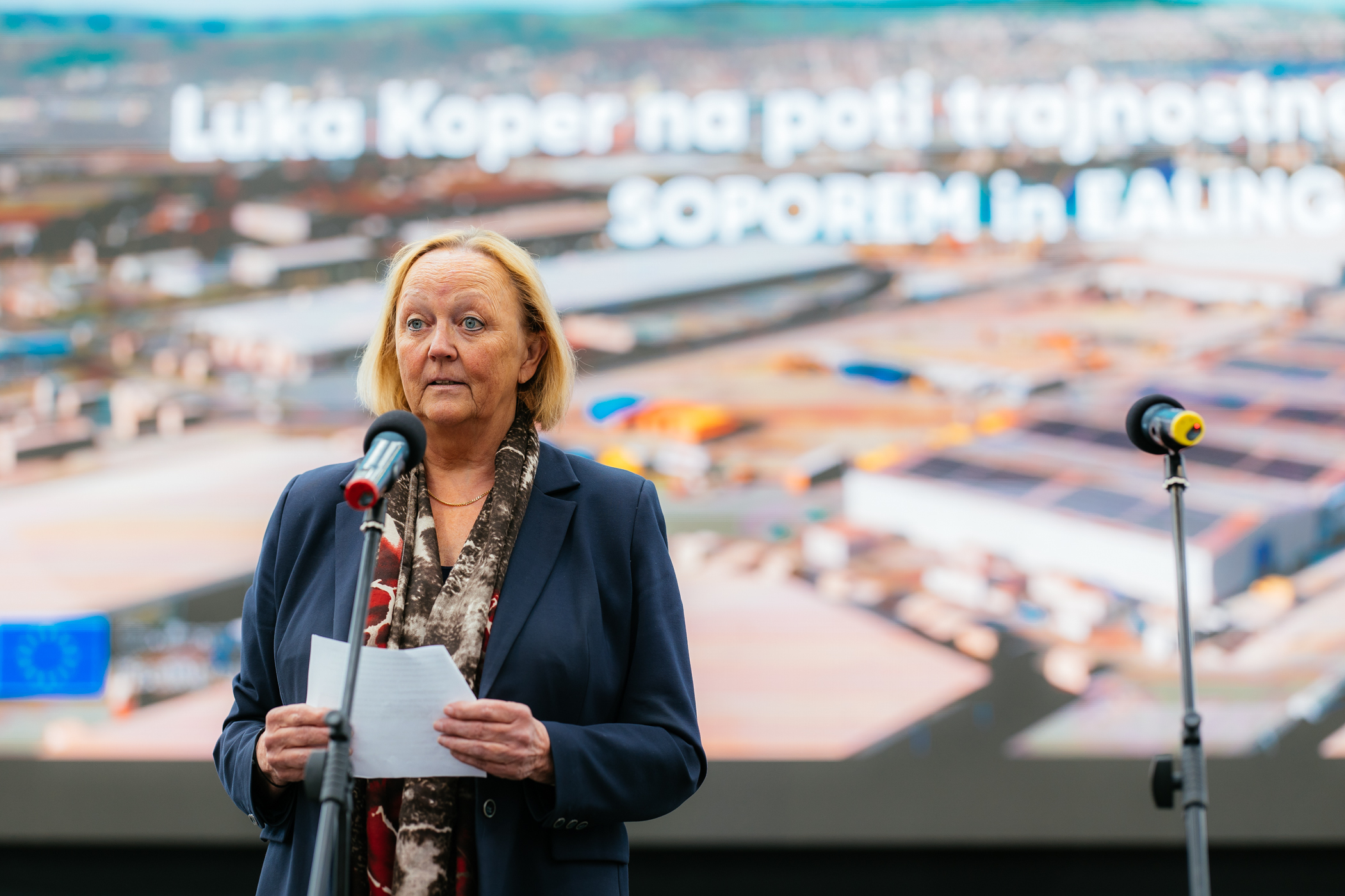 The Ambassador of the Kingdom of Norway stands on stage in front of a standing microphone and delivers a speech.