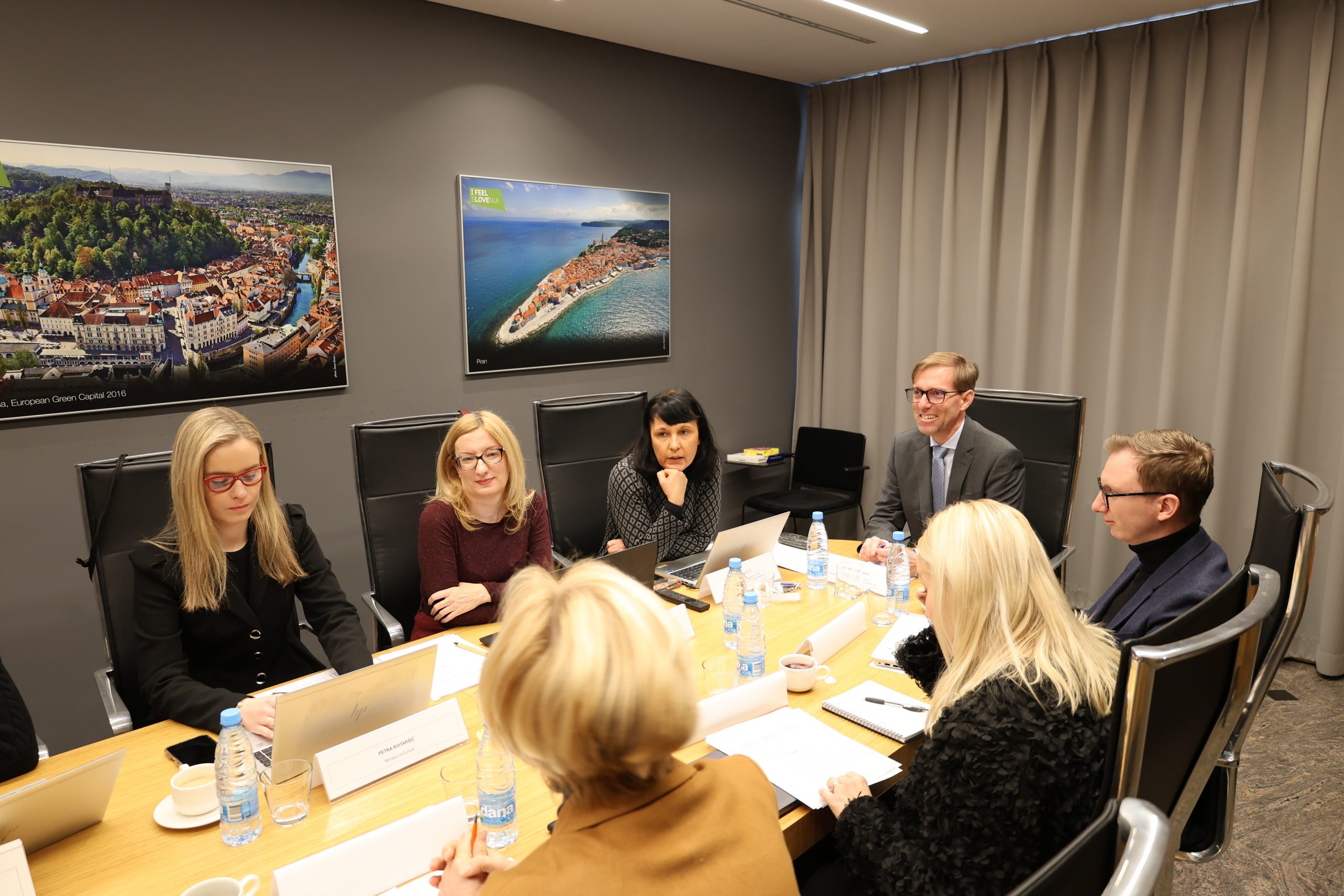 Udeleženci strokovnega posveta sedijo za mizo in sestankujejo.